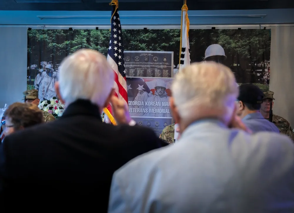 Korean War veterans saluting during the National Anthem at a 2024 Armistice Day commemoration