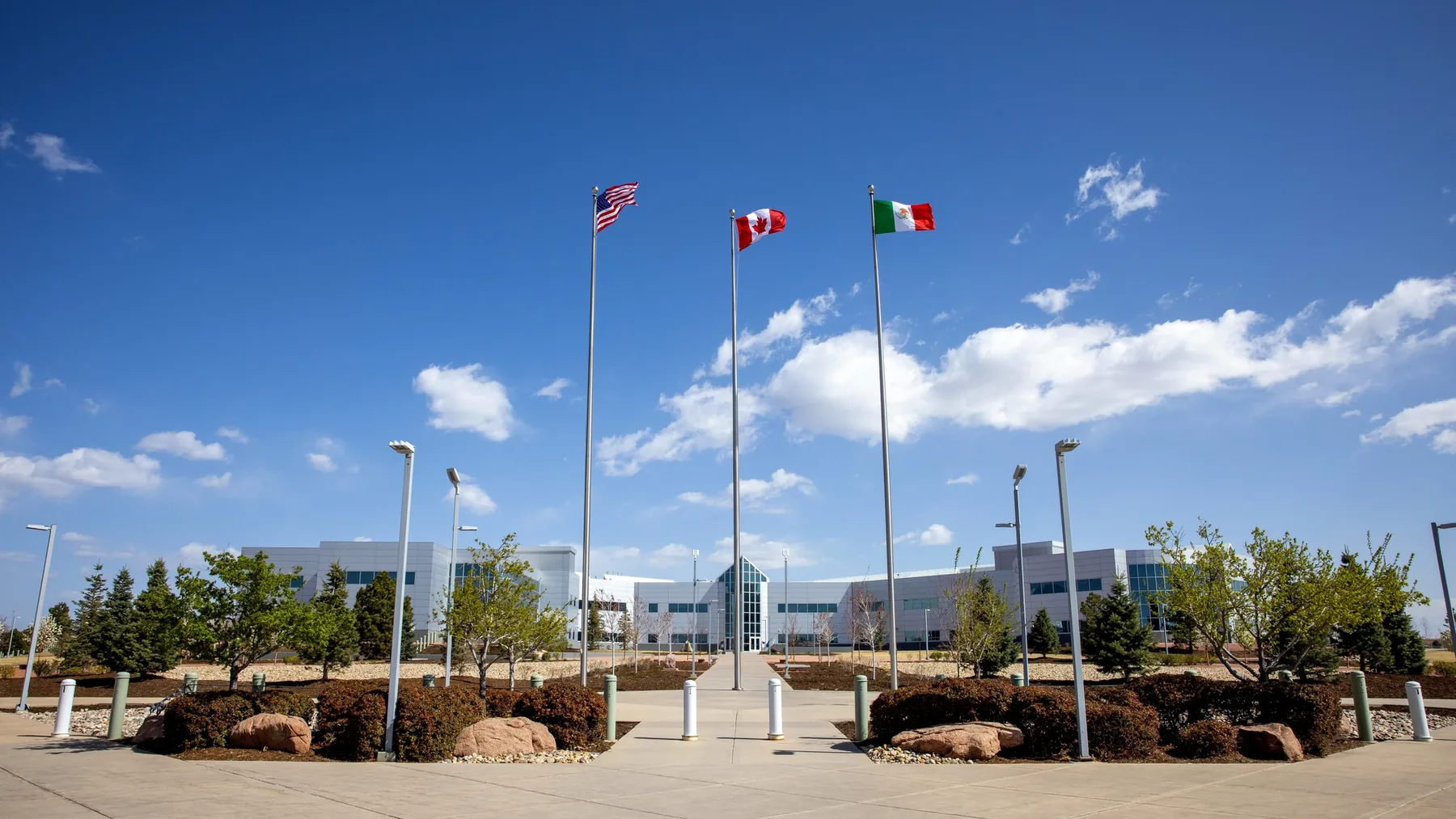 United States, Canadian, and Mexican flags on separate equal-height flagpoles