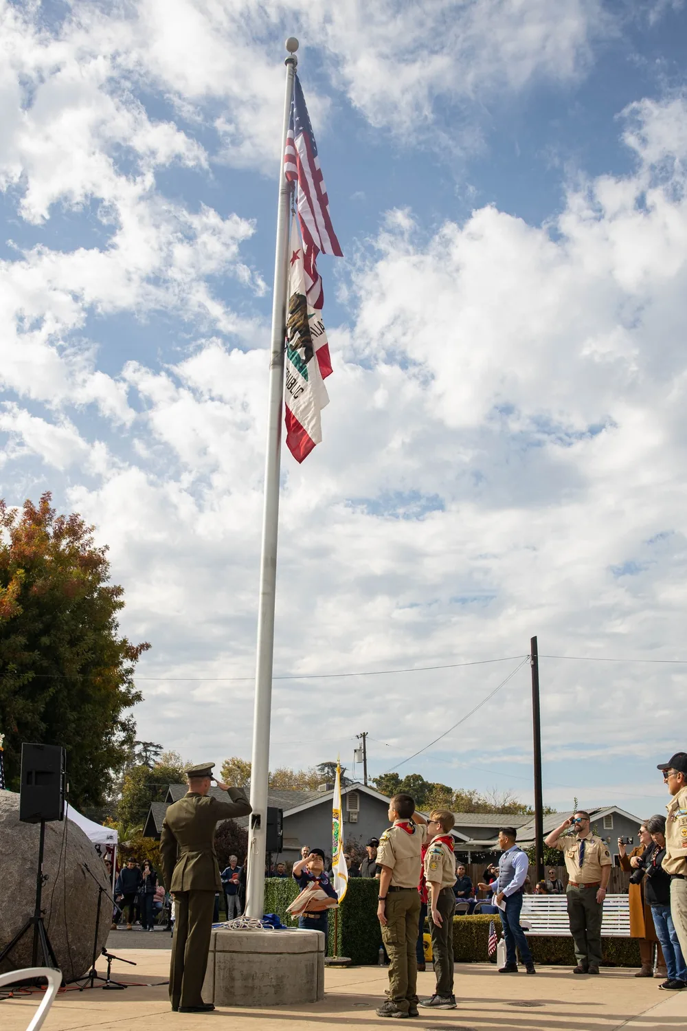 A Marine and ceremony participants salute beside a flagpole in Fowler, California