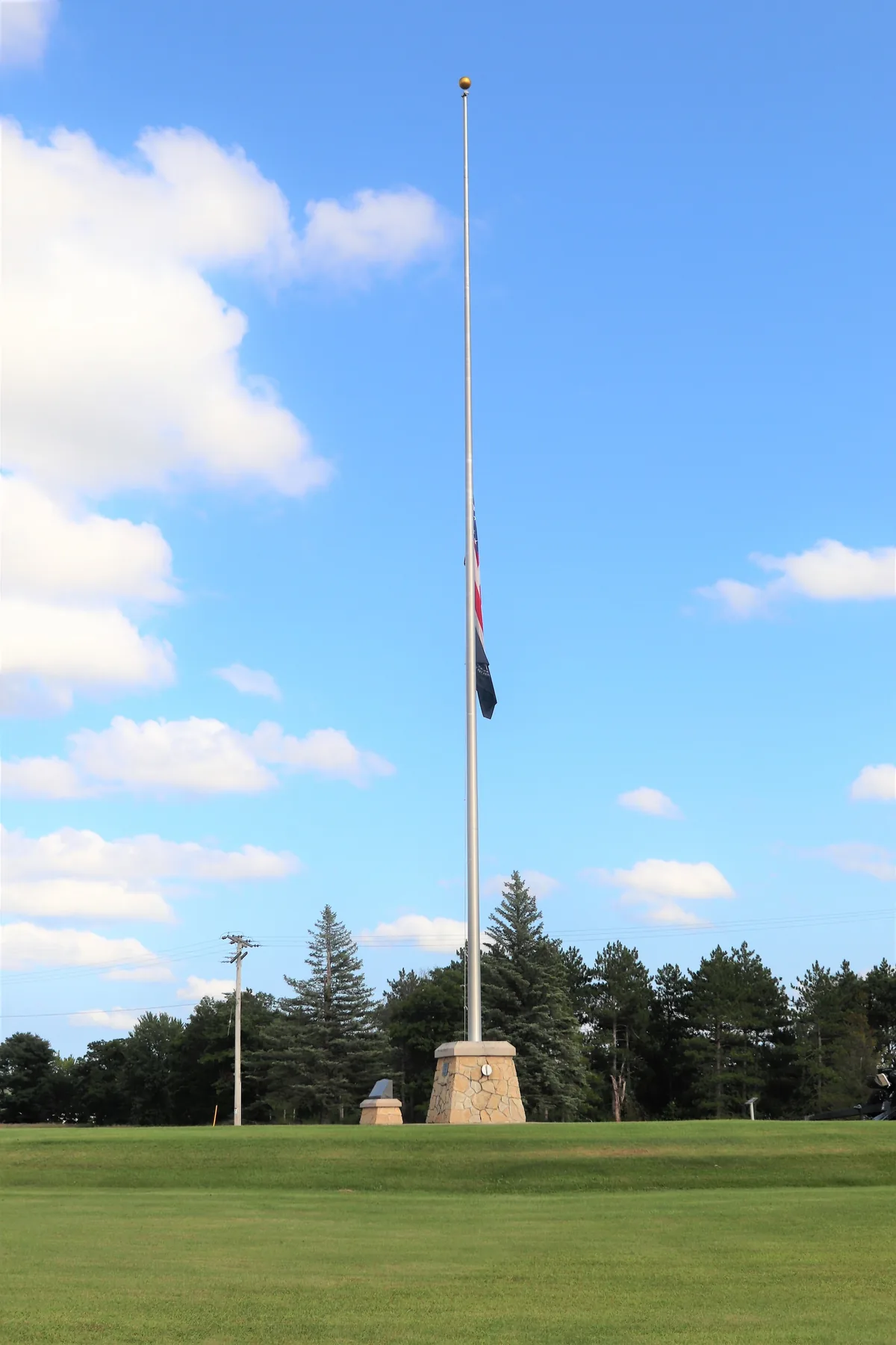 United States flag flying at half-staff on a tall pole at Fort McCoy